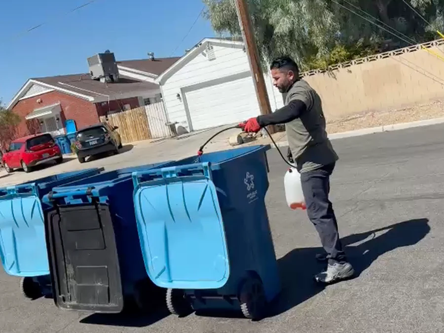 Perez Power Wash technician moving three residential trash bins into position for cleaning in North Las Vegas