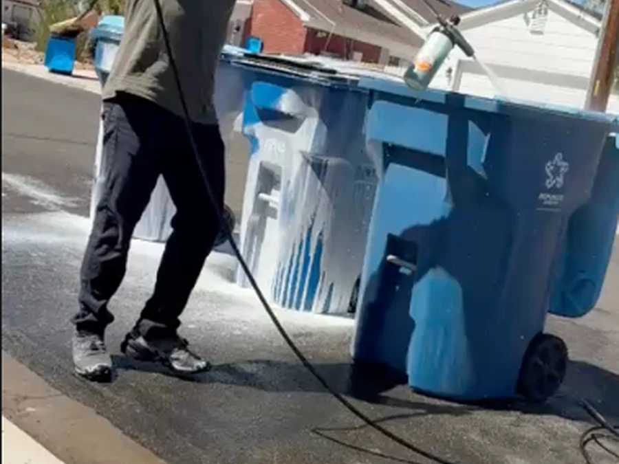 High pressure hot water rinse blasting grime off a curbside trash bin